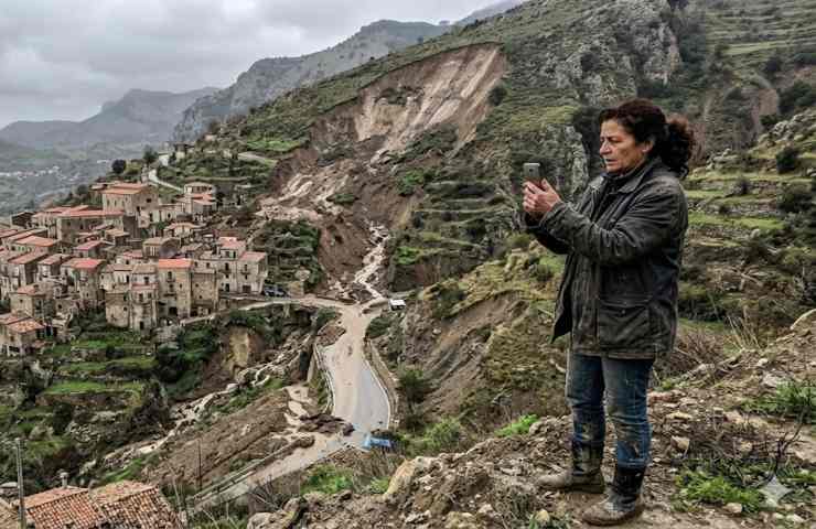 Donna che fotografa territorio colpito da frana